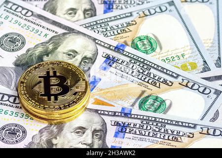 Monete in bitcoin d'oro (BTC) su sfondo di banconote 100 dollari US fattura. Concetto di moneta virtuale e di cripto-valuta digitale. Foto Stock