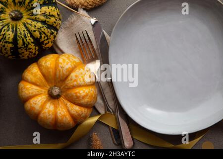 Cena a tavola in autunno con posate di zucca e piatto vuoto Foto Stock