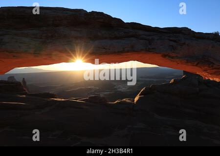 Mesa Arch e alba come il sole cime attraverso le nuvole e l'arco Foto Stock