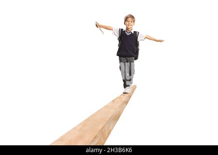 Scolaro in uniforme con uno zaino che cammina su un fascio di legno isolato su sfondo bianco Foto Stock