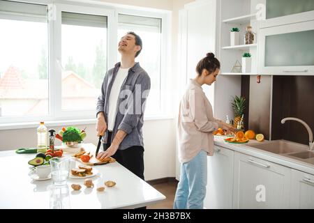 Coppia felicemente passare il fine settimana insieme in cucina dove preparano un pranzo sano. Pranzo vegetariano. Cena romantica. Foto Stock