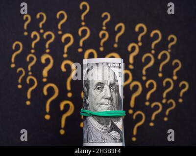 Una pila legata di 100 dollari fatture contro un punto interrogativo sfondo. Primo piano Foto Stock
