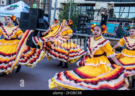 2021 10 09 Tulsa USA Dancing le ragazze ispaniche rotellano i loro bei costumi gialli mentre ballano in un festival di strada di fronte a uno stange e diffusori Foto Stock