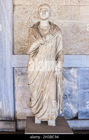 Antica statua greca dell'uomo in toga contro la lavorazione del marmo e del legno e il muro di cemento Foto Stock