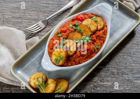 Riso Jollof con plantain fritto - piatto piccante di riso africano vegetariano Foto Stock