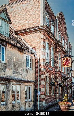 Luglio 25 2019 Lacock UK vista laterale del Red Lion Inn - edifici storici in incontaminata città britannica con appeso segno e piante Foto Stock
