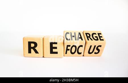 Simbolo di rifocalizzazione e ricarica. L'uomo d'affari girò i cubi e cambiò la parola 'focus' in 'ricarica'. Bella tavola bianca, sfondo bianco. Affari Foto Stock
