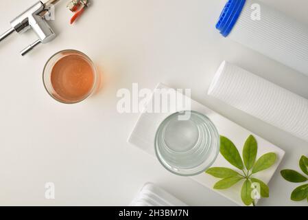 Confronto di acqua sporca e filtrata da osmosi in bicchieri su un banco da cucina con filtro e attrezzatura. Vista dall'alto. Composizione orizzontale. Foto Stock