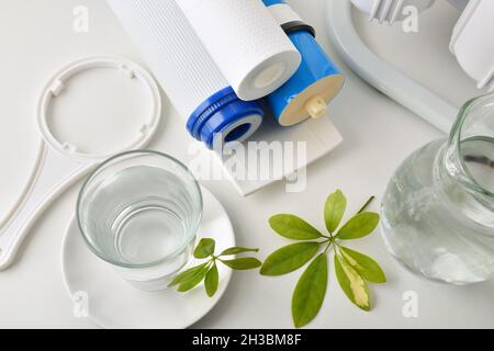 Bicchiere di acqua depurata con attrezzatura domestica e filtri su tavolo e cucina in background con attrezzatura per osmosi. Vista dall'alto. Comp. Orizzontale Foto Stock