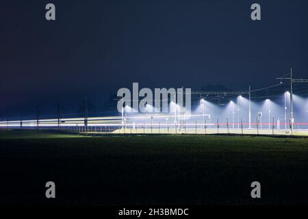 Sentiero leggero del treno. Traffico sulla ferrovia elettrificata di notte. Foto Stock