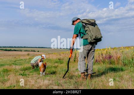 Un uomo e una donna cercano gioielli con un rivelatore di metalli e una pala. Foto Stock