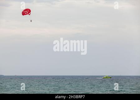 Parasailing nella baia di Agia Napa, motoscafo e paracadute rosso Foto Stock