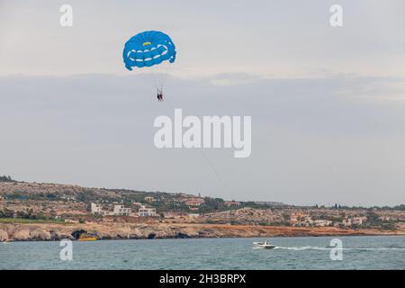 Paracadutismo in località di Agia Napa, motoscafo e paracadute blu con turisti Foto Stock