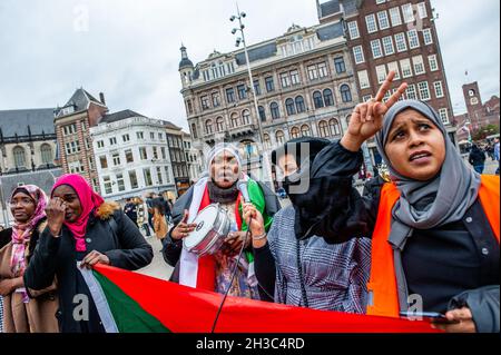 Amsterdam, Paesi Bassi. 27 ottobre 2021. Una donna sudanese ha visto fare un simbolo di pace mentre un'altra sta suonando un tamburo durante la dimostrazione.la gente sudanese che vive nei Paesi Bassi si è riunita a Piazza Dam nel centro della città di Amsterdam per protestare contro il colpo di stato militare in Sudan. Lunedì il leader del colpo di stato Gen Abdel Fattah Burhan sciolse il governo civile, arrestò i leader politici e chiamò lo stato di emergenza. Un gran numero di manifestanti si trova nelle strade della capitale che chiede il ritorno del dominio civile. Credit: SOPA Images Limited/Alamy Live News Foto Stock