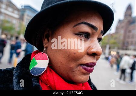 Amsterdam, Paesi Bassi. 27 ottobre 2021. Una donna sudanese ha visto indossare orecchini con la bandiera del Sudan durante la manifestazione. I sudanesi che vivono nei Paesi Bassi si sono riuniti in Piazza Dam nel centro della città di Amsterdam per protestare contro il colpo di stato militare in Sudan. Lunedì il leader del colpo di stato Gen Abdel Fattah Burhan sciolse il governo civile, arrestò i leader politici e chiamò lo stato di emergenza. Un gran numero di manifestanti si trova nelle strade della capitale che chiede il ritorno del dominio civile. (Foto di Ana Fernandez/SOPA Images/Sipa USA) Credit: Sipa USA/Alamy Live News Foto Stock