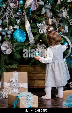 Piccolo caugher decorare l'albero di Natale a casa. Famiglia, x-mas, vacanze invernali e persone concetto. La famiglia con i bambini festeggia le vacanze invernali. Foto Stock