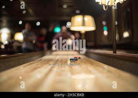 Puck blu e rosso su un tavolo per shuffleboard Foto Stock