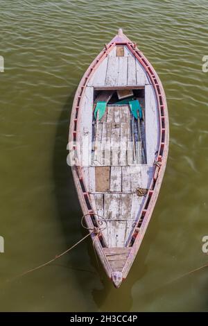 Piccola barca vicino a Ghats lungofiume gradini che conducono alle rive del fiume Ganges in Varanasi, India Foto Stock