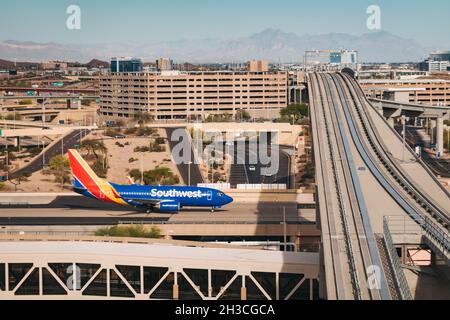 Un Boeing 737 di Southwest Airlines con i treni PHX Sky Train all'aeroporto Sky Harbor di Phoenix, Arizona, USA Foto Stock