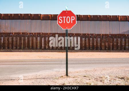 Un segnale di stop di fronte al muro di confine in acciaio USA-Messico nella città di Naco, Arizona, Stati Uniti Foto Stock