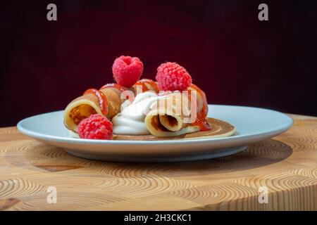 Helsinki / Finlandia - 27 OTTOBRE 2021: Un piatto di soffici pancake norvegesi con panna montata caramellata e confettura di lamponi sul lato. Foto Stock