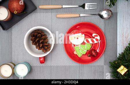 Decorazioni da tavolo natalizie con candele profumate e un piatto di biscotti con zucchero a tema natalizio. Foto Stock