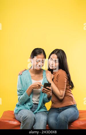 una ragazza piange purtroppo guardando il telefono cellulare mentre si appoggia sulla spalla del suo amico Foto Stock