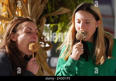 Maryland Heights, Stati Uniti. 27 ottobre 2021. Jackie o'Brian (L) e Layla Amis si godono le mele caramelle mentre si visita la Ties Farm e Greenhouses durante le esposizioni di Halloween, in Maryland Heights, Missouri mercoledì 27 ottobre 2021. Foto di Bill Greenblatt/UPI Credit: UPI/Alamy Live News Foto Stock