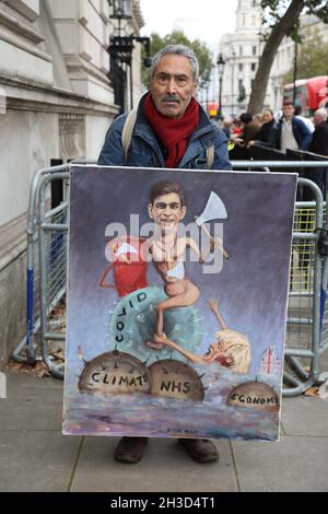 Londra, Regno Unito. 27 ottobre 2021. L'artista Kaya Mar tiene il suo dipinto di Rishi Sunak il Cancelliere dello scacchiere fuori Downing Street il giorno di bilancio. Budget Day, Downing Street, Westminster, Londra, ottobre 27, 2021. Credit: Paul Marriott/Alamy Live News Foto Stock