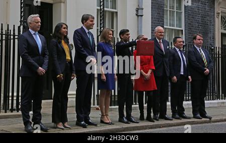 Londra, Inghilterra, Regno Unito. 27 ottobre 2021. Il Cancelliere dello scacchiere, RISHI SUNAK (C) detiene la scatola del bilancio nella sua forma attuale con i membri del suo team del Tesoro, tra cui ROB BUTLER MP (L), Segretario privato parlamentare al Tesoro CLAIRE COUTINHO (2°, L), Segretario economico al Tesoro JOHN GLEN (3°, L), Segretario finanziario al Tesoro LUCY FRAZER (4th L), Segretario dello scacchiere al Tesoro HELEN WHATELY (4th, R), Ministro di Stato Lord AGNEW (3rd, R), Signore Commissario del Tesoro ALAN MAK (2nd, R) e Segretario privato parlamentare al Capo Segretario CRAIG WIL Foto Stock