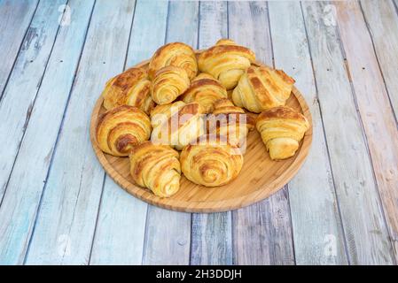 Piatto di legno di bambù riempito con mini croissant al burro per uno spuntino Foto Stock