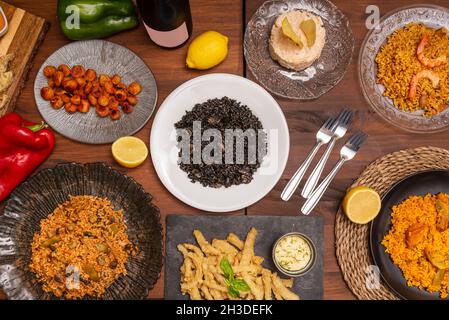 Immagine dall'alto di un set di piatti spagnoli e paella di riso nero e paella valenciana con verdure e pollo, calamari con salsa aioli Foto Stock