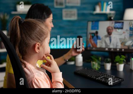 Madre che ha consulenza medica virtuale discutere di trattamento pillole con il medico terapista remoto durante la conferenza on-line videocall riunione. Chiamata Telemedicine sullo schermo del computer in quarantena Foto Stock