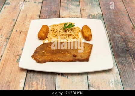 Schnitzel di vitello con spaghetti e crocchette su piatto bianco Foto Stock
