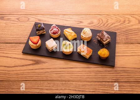 Vassoio di tortini assortiti con frutta, panna, cioccolatini, marmellate e noci Foto Stock