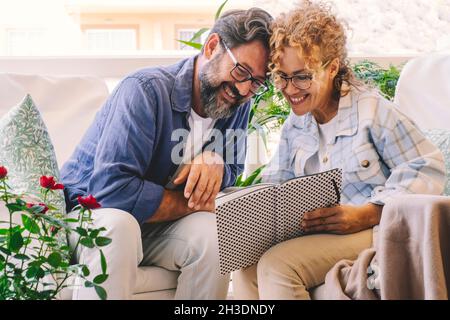 Uomo e donna felici e allegri che leggono insieme un notebook fuori casa. La coppia caucasica è piaciuta e prende appunti e legge con sorriso. Adulti persone Foto Stock