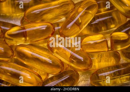 Capsule di olio grasso di pesce Omega-3 come tessuto di fondo. EPA e DHA sono sostanze grasse essenziali di cui il nostro corpo ha bisogno quotidianamente. Foto Stock