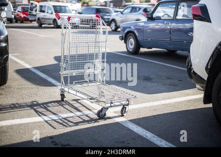 Carrello vuoto per lo shopping si trova in un parcheggio di strada nel centro di un centro commerciale e in auto. Foto Stock