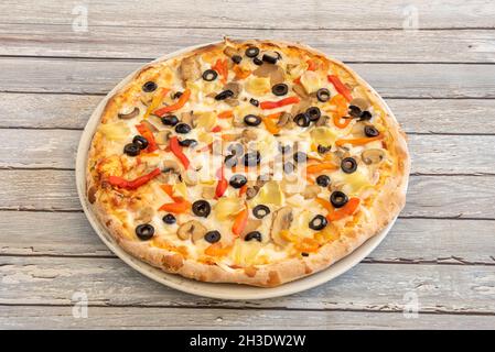 Pizza vegana con formaggio di patate con fette di olive nere, fette di funghi, foglie di carciofo e peperoni arrostiti Foto Stock