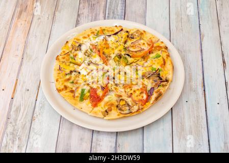 Pizza di verdure con formaggio di patate, mais dolce, cipolla rossa, pomodoro sbriciolato, cipolla rossa, fette di funghi e origano Foto Stock