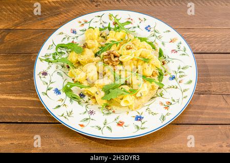 Ricetta italiana per ravioli ripieni di stufato di pera, servire con olio d'oliva, noci della California e foglie di rucola. Foto Stock
