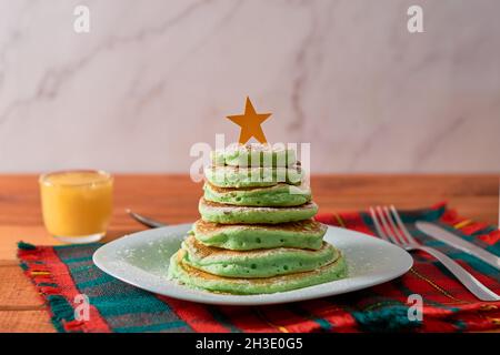 Frittelle a forma di albero di Natale sul tavolo. Colazione di Natale Foto Stock