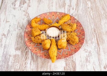 Assortimento di pezzi di pollo ricoperti di farina, pangrattato, uova e salsa al formaggio per l'immersione Foto Stock