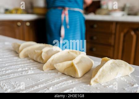 Sul tavolo giacciono i manti grezzi triangolari. Preparazione della cottura Foto Stock