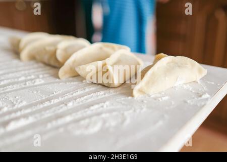 Sul tavolo giacciono i manti grezzi triangolari. Preparazione della cottura Foto Stock