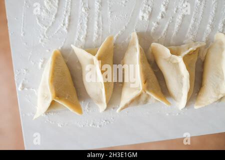 Sul tavolo giacciono i manti grezzi triangolari. Preparazione della cottura Foto Stock