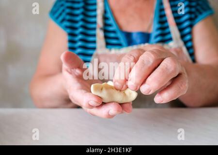 Una donna anziana scolpisce con le mani un piatto di pasta Foto Stock