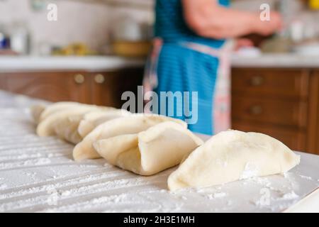 Sul tavolo giacciono i manti grezzi triangolari. Preparazione della cottura Foto Stock