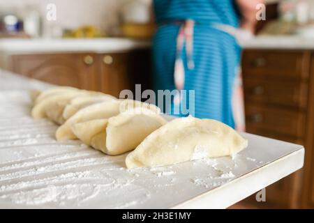 Sul tavolo giacciono i manti grezzi triangolari. Preparazione della cottura Foto Stock