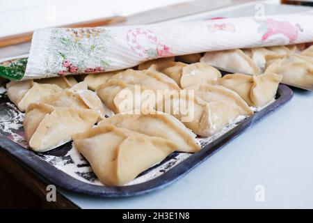 i manti crudi che si trovano sul tavolo sono appena stati accecati. Un piatto di pasta. Ricetta della nonna Foto Stock